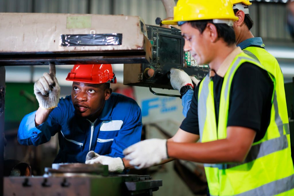 Training trainee concept. Yang male african american engineer explain the procedure for using the correct metal machine at factory.